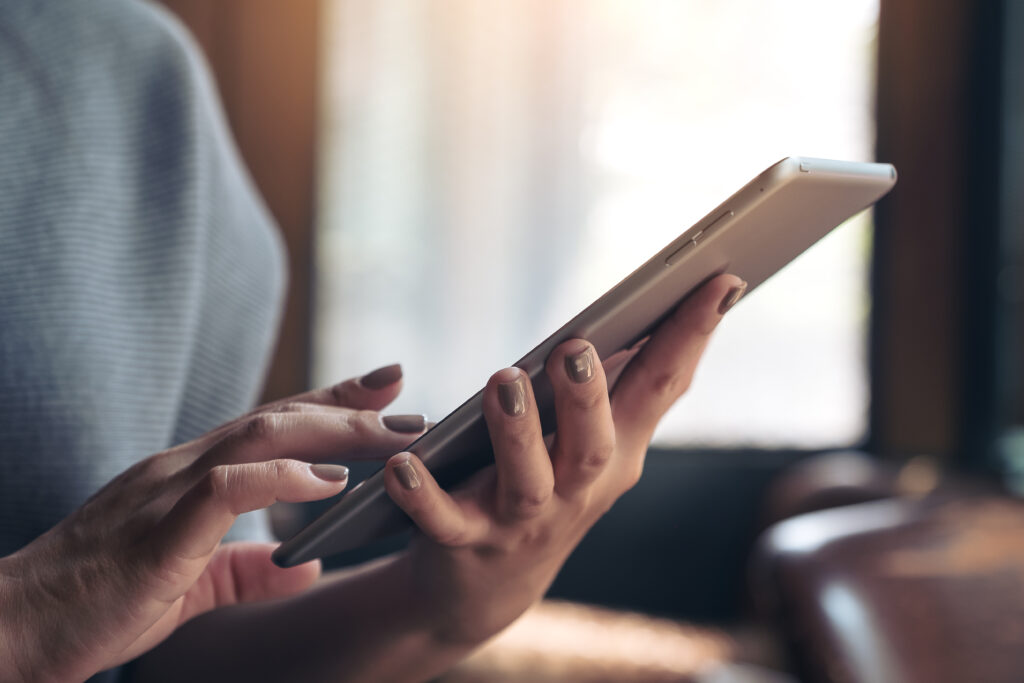 Closeup image of hands holding and using tablet pc in cafe